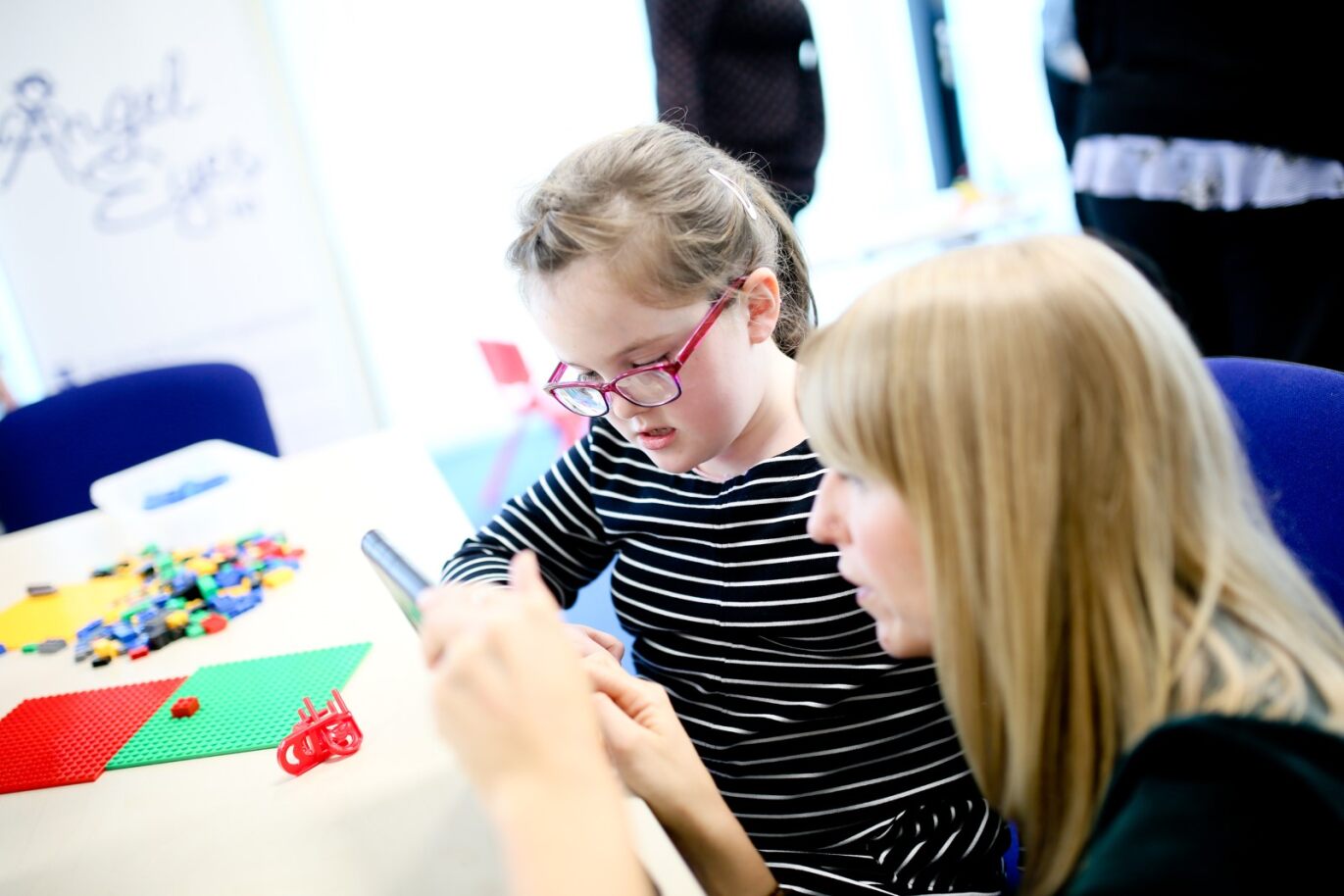 This image shows a young girl being taught how to use the accessibility features of the iPad by our Education Advocate at an Accessibility workshop.